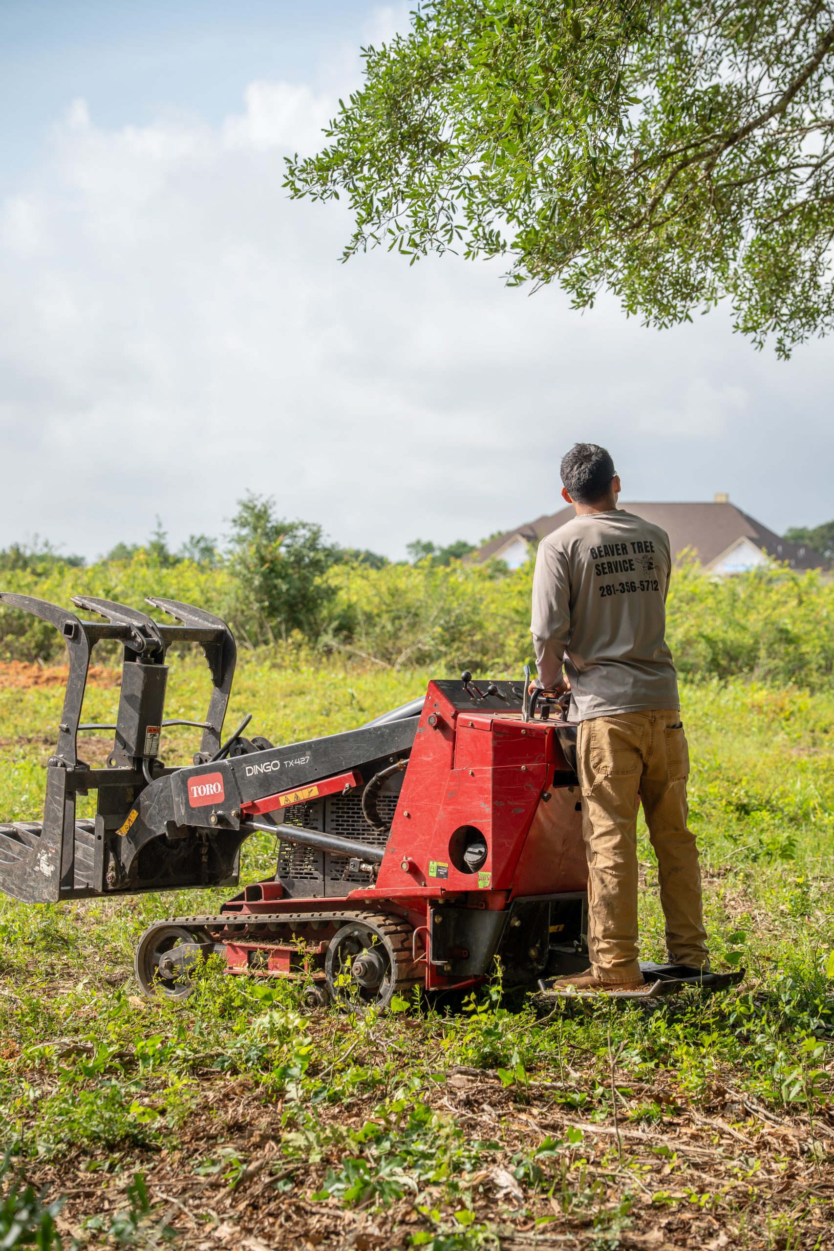 A woodchipper operates in a grassy field during a land clearing job.