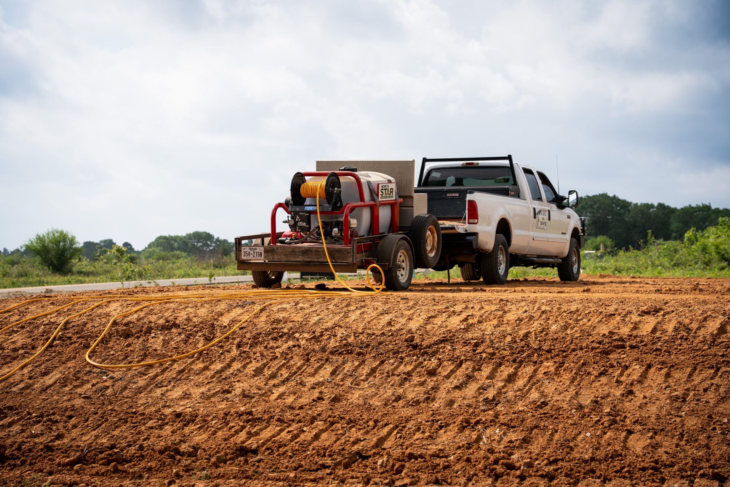 A tree service truck with equipment parked on a cleared dirt lot.
